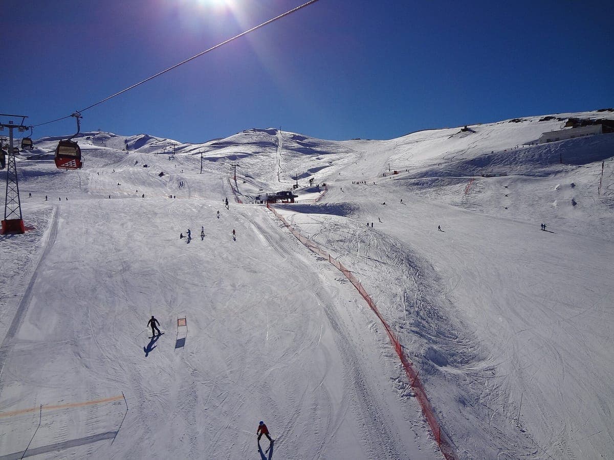 A groomed piste and the gondola line at Valle Nevado under a deep blue sky