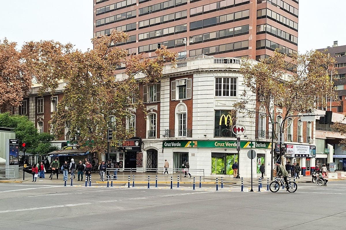 A corner of Avenida Providencia with shops, autumn trees and pedestrians