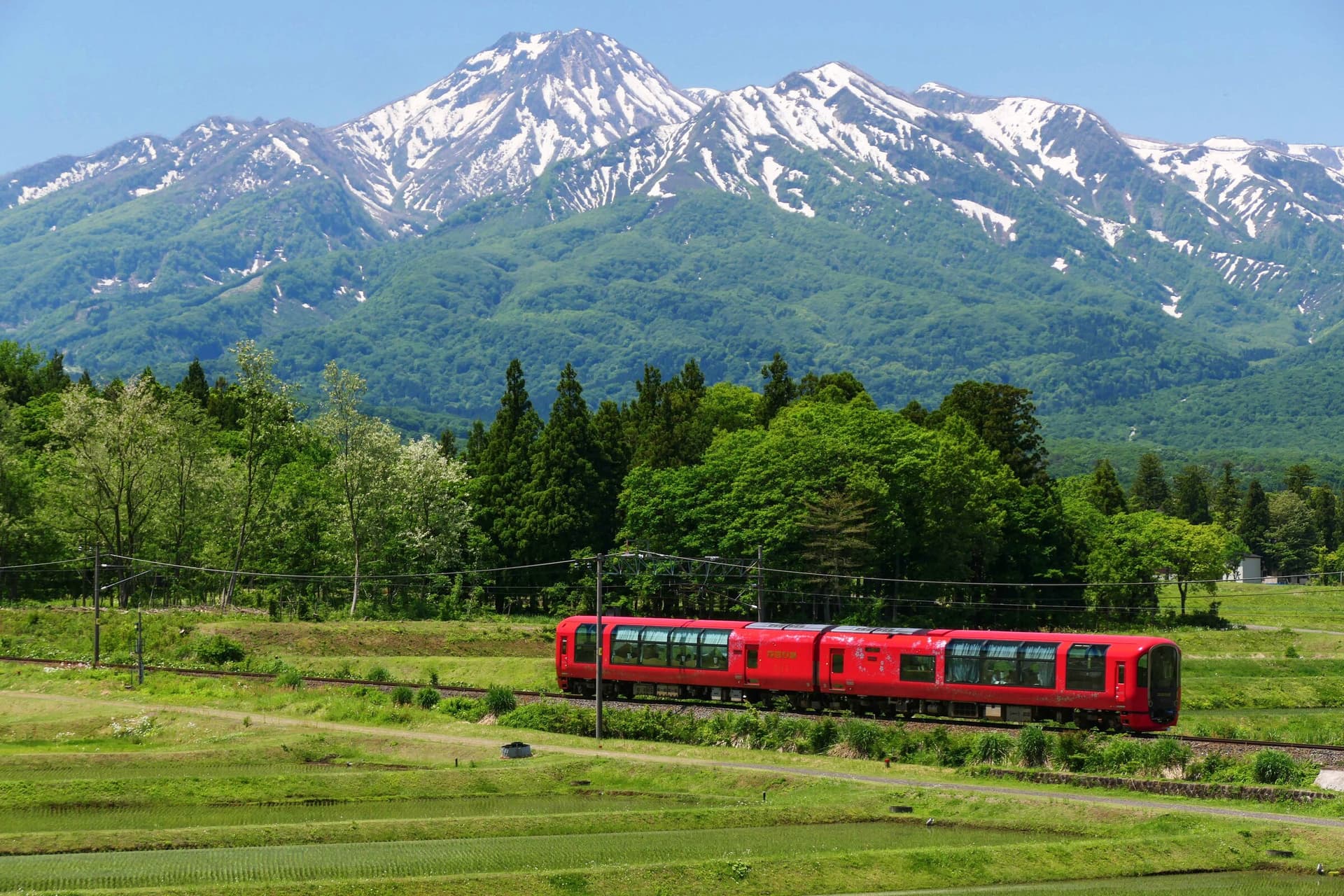 The Myoko Haneuma Line's red Setsugekka train below snow-streaked Mount Myoko
