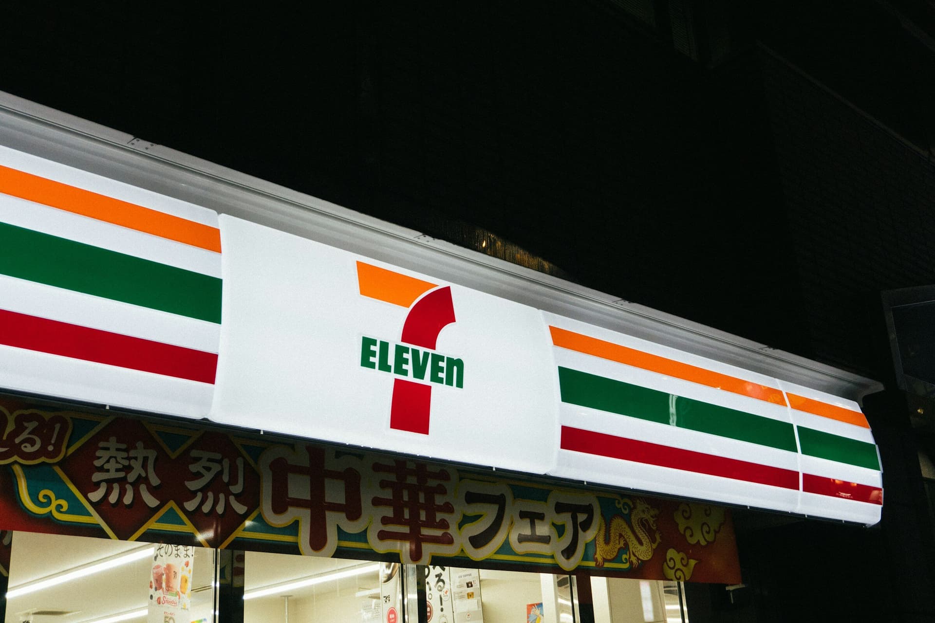 A 7-Eleven storefront lit up at night in Japan