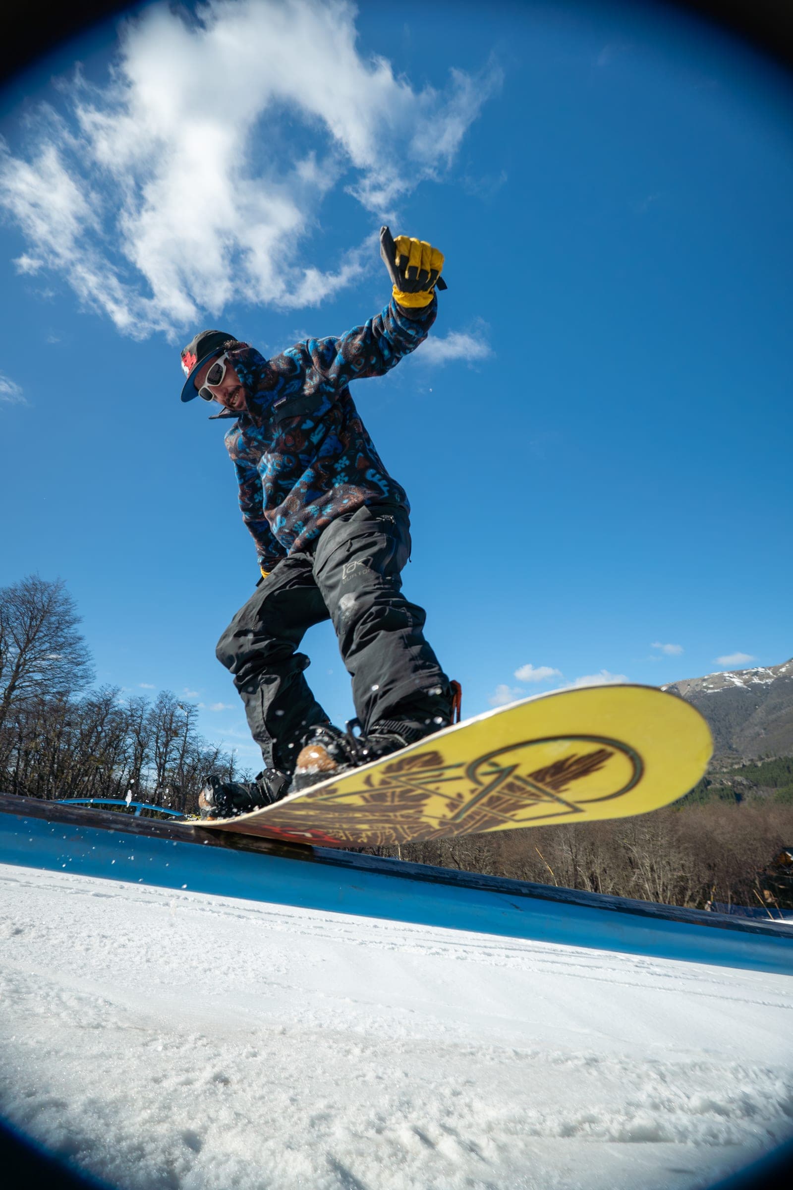 Snowboarder pressing a rail under a clear blue sky in Bariloche